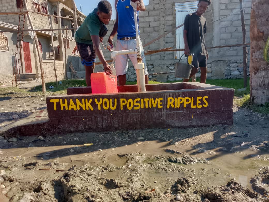 A community well in Haiti with 'THANK YOU POSITIVE RIPPLES' painted across the basin.